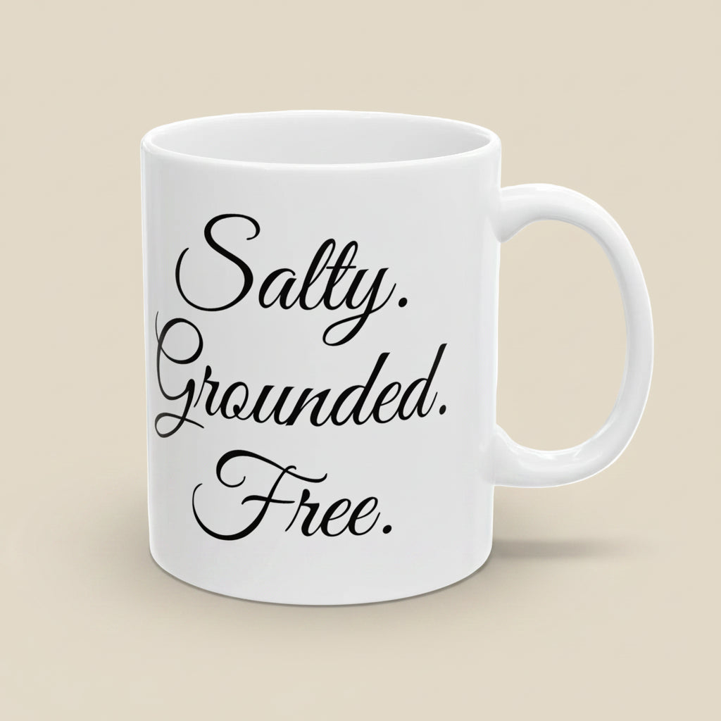 White mug with black text 'Salty. Grounded. Free.' on a white background
